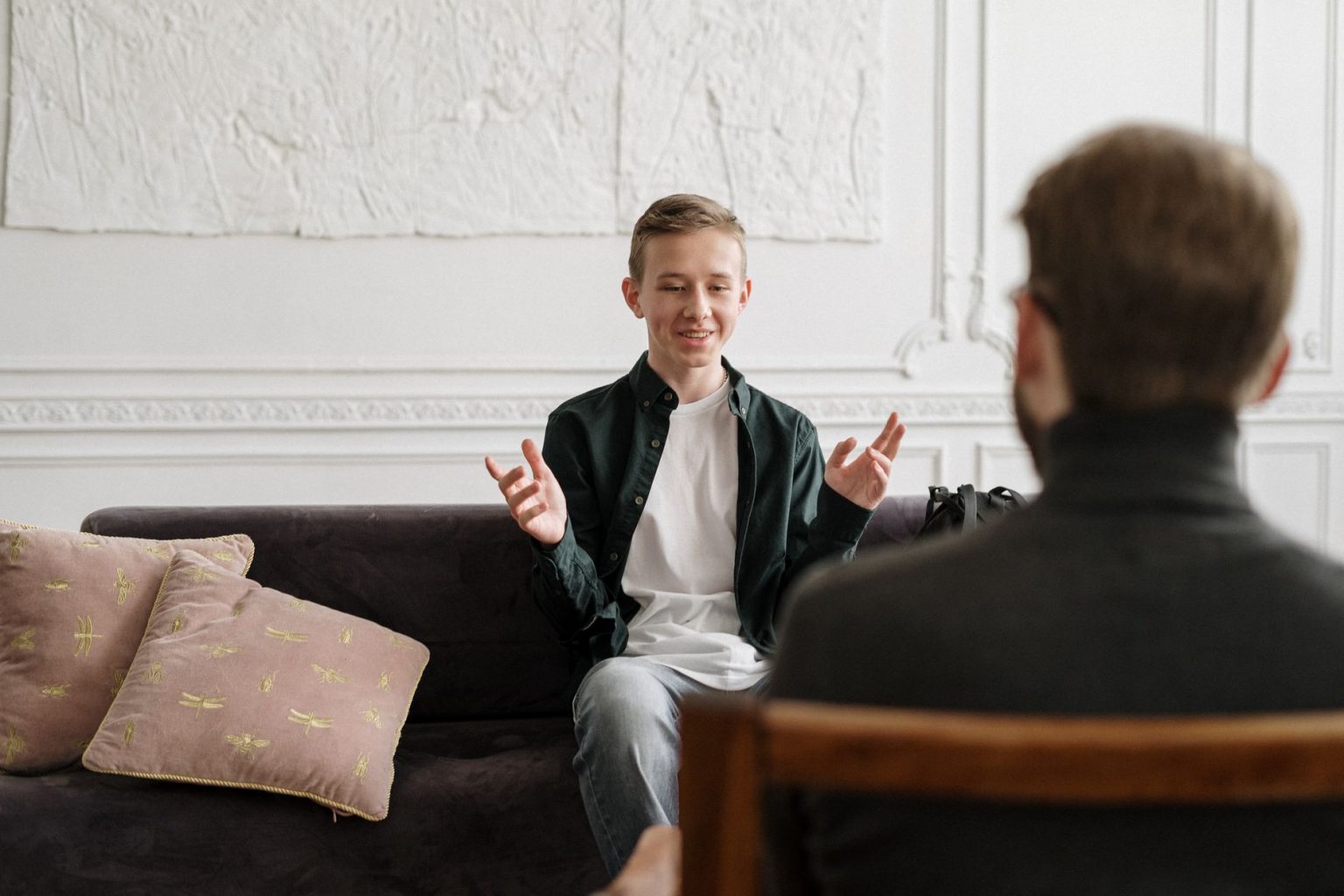 Adolescente conversa com uma terapeuta sentada em um sofá durante uma sessão de atendimento.