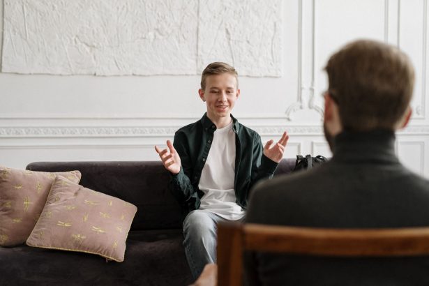 Adolescente conversa com uma terapeuta sentada em um sofá durante uma sessão de atendimento.