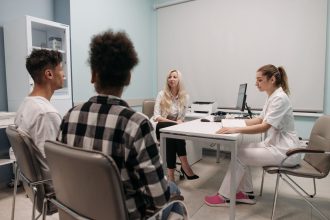 Jovens conversam com profissionais de saúde durante uma consulta em um consultório.
