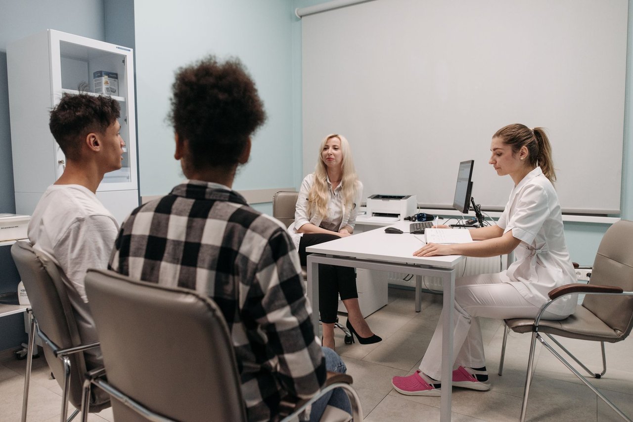 Jovens conversam com profissionais de saúde durante uma consulta em um consultório.